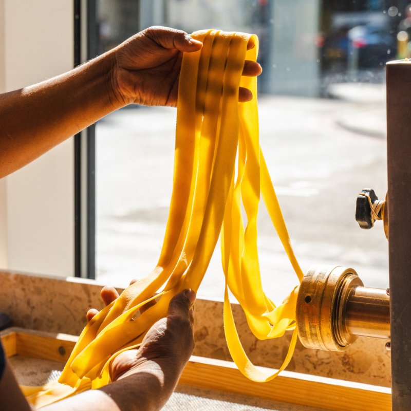 long wide pasta ribbons coming out of a pasta machine